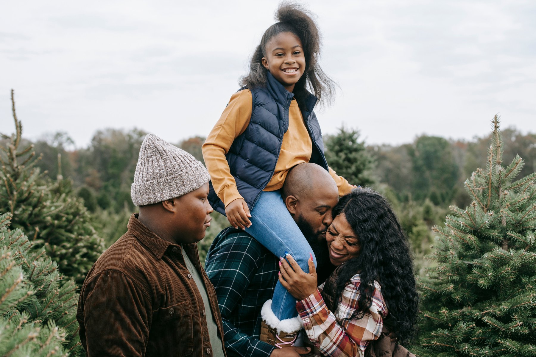 Cheerful black family having fun together among spruce